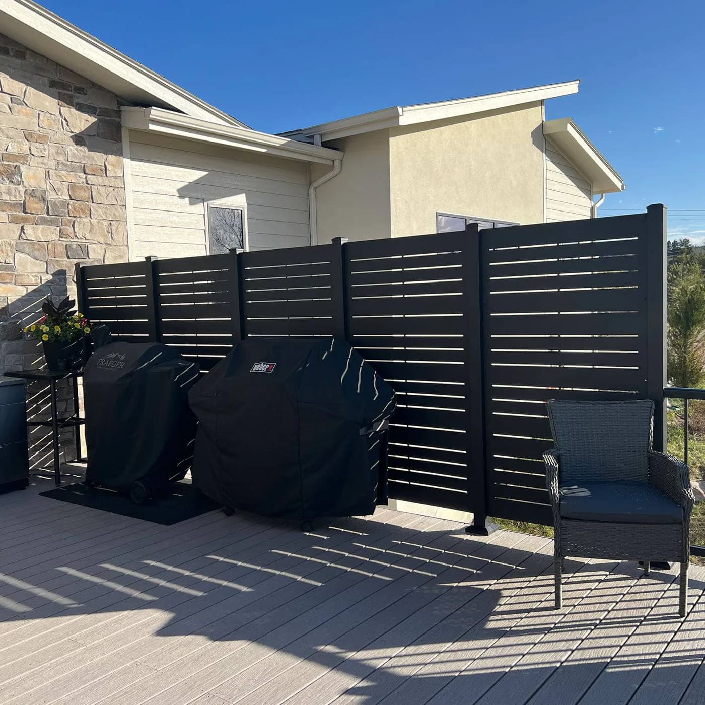 Black aluminum slatted privacy wall on a composite deck by Vivid Outdoor Living