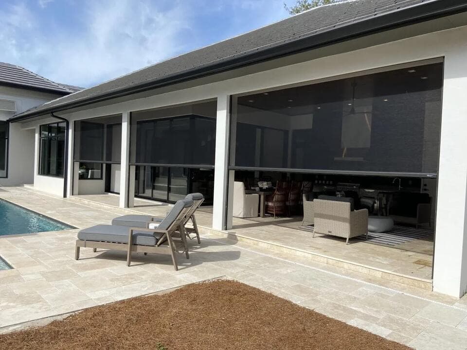 Modern home with motorized retractable screen room enclosure by Vivid Outdoor Living